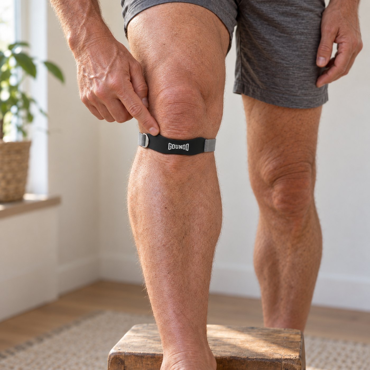 The knee strap seated directly below the kneecap, a fingertip on the soft spot above the pad
